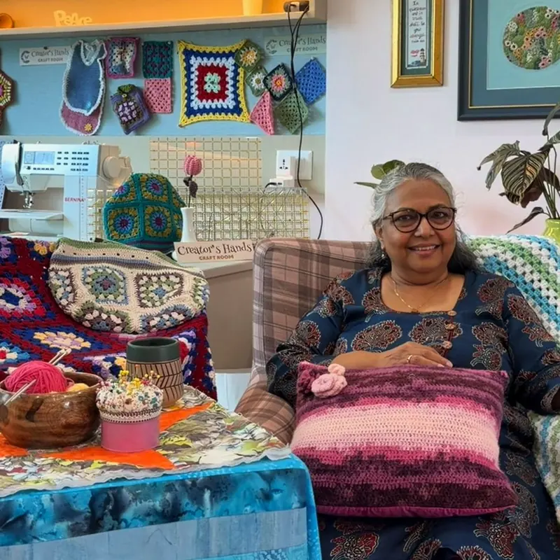 Rhoda Staneley, founder of Creator's Hands Craft Room, in the studio with a crocheted cushion