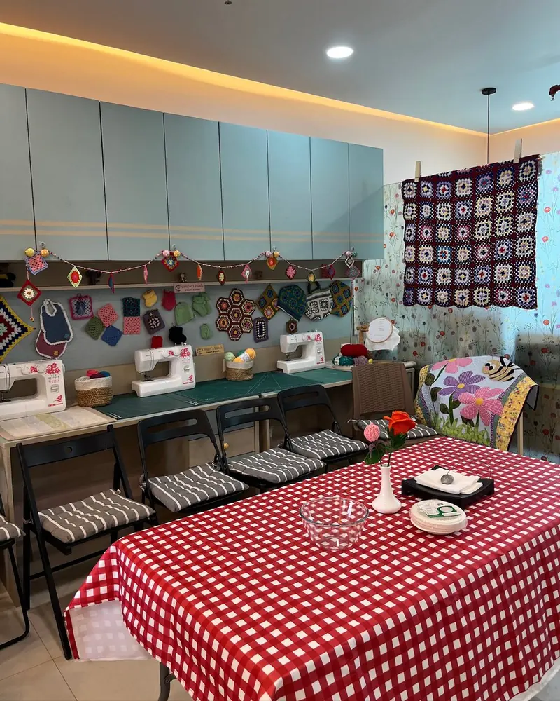 Inside the Creator's Hands craft room in Kharadi: sewing machines, a wall of crochet work and a gingham-covered table