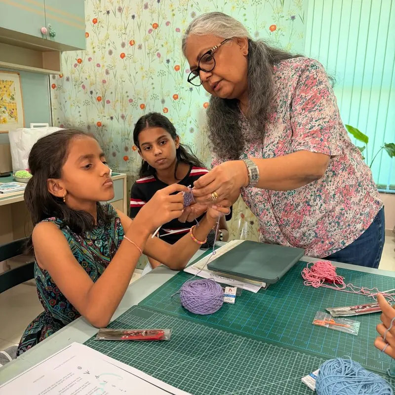 Rhoda showing two young makers a crochet stitch at the studio